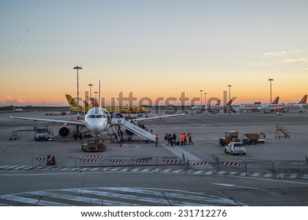 MILAN, ITALY - NOV 18: People board a commercial airplane at Milan Malpensa airport at sunset in Milan on November 18, 2014