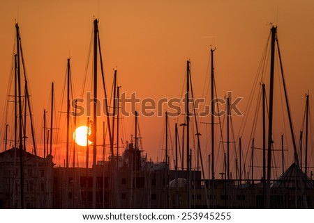 Beautiful sunset in the marina - Red sun sets behind boats masts