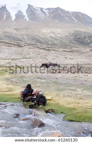 TSO MORIRI, INDIA - JULY 21: Unidentified nomads washing pots near Tso Moriri, July 21 2009. Changpa herders use the land as grazing ground and for cultivation at an altitude of circa 15.000 ft asl