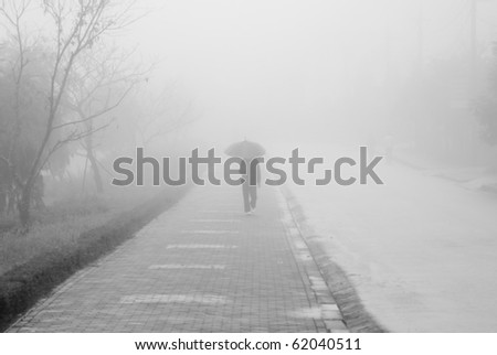 Human figure with umbrella walking in the mist