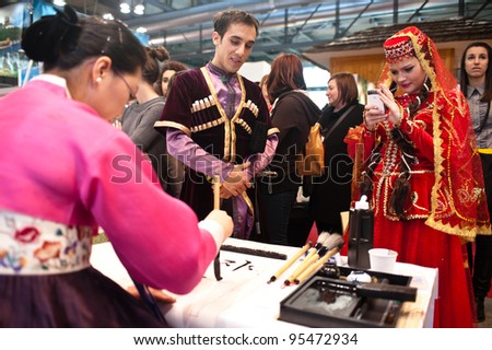 MILAN, ITALY - FEBRUARY 17: A dancer from Azerbaijan takes a picture at a korean woman at BIT International Tourism Exchange on february 17, 2012 in Milan, Italy.