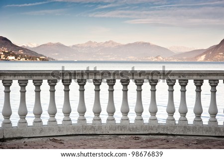 A classical column banister faces the tranquil waters of Lake Maggiore in Italy