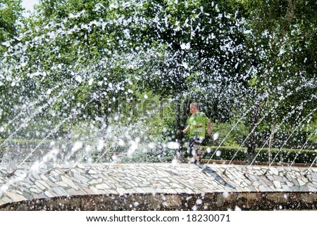 Fountain. Hot summer. Boy under the sprays of the water 2.