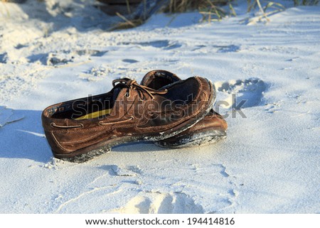 Color DSLR picture of weathered brown boat shoes on the beach sand by the shore; in horizontal orientation with copy space for text