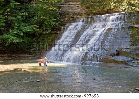 Two boys playing in a waterfall pond; in horizontal orientation with copy space for text