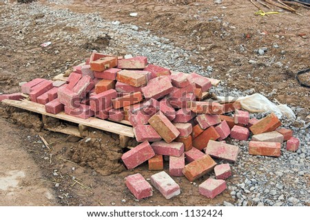 Color DSLR picture of a pile of red bricks on the ground at a construction site. Horizontal orientation with copy space for text