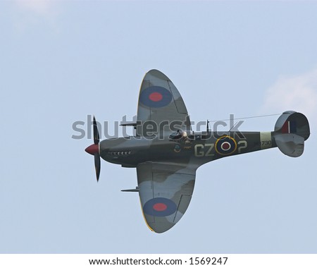 Color DSLR picture of a famous, British WWII Spitfire fighter airplane flying. Propeller plane helped fight Battle of Britain in war. Horizontal with copy space for text.