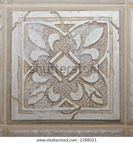 Color DSLR picture of square off white, tan or beige decorative ceramic tile with a textured pattern.