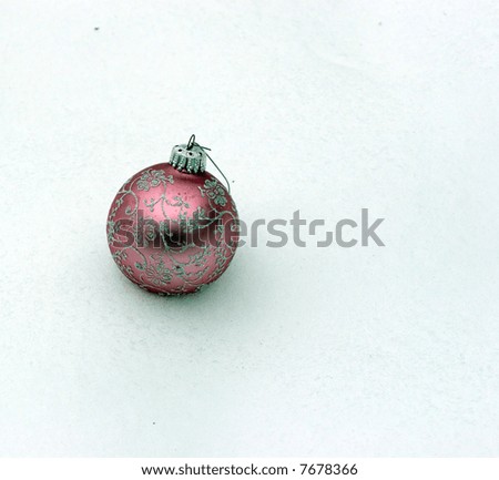 Color DSLR image of round, pink and silver Christmas holiday ornament. Shiny, festive holiday decoration sitting in the white winter snow. Horizontal with copy space for text.