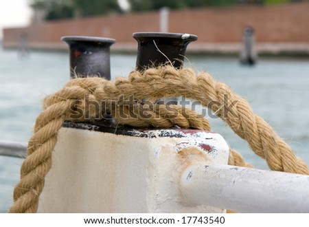 Nautical rope, tied on cleat, with water in the background