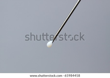 Sharp syringe with a drop of white medicine; in horizontal orientation, with copy space for text