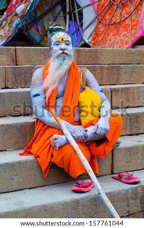 VARANASI, INDIA - OCT 1: An unidentified  sadhu with traditional painted face and body, sits at the ghat along the Ganges on October 1, 2013 in Varanasi, India.