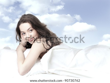 pretty girl sleeping on the white linen on background of clouds