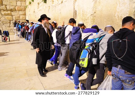 JERUSALEM, ISRAEL - MARCH 22, 2015: Orthodox judaism teacher in prayer time with his pupils close to the Western wall in Jerusalem old  city.