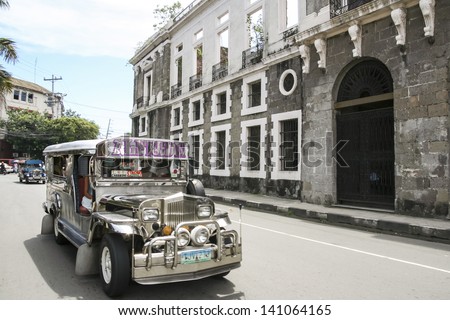 MANILA - JULY 10: jeepney public transport driving past derelict building in intramuros on 10 July 2009 in manila. Jeepneys are the most popular means of public transportation in the Philippines.