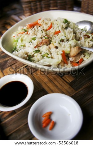 bowl of chicken and rice with side portions of chillies and soy sauce served filipino style on bamboo table