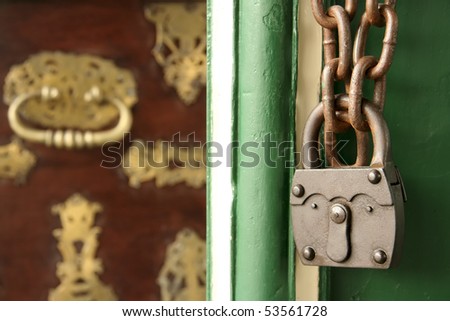 old rusty metal padlock and chain, with old wooden chest in background