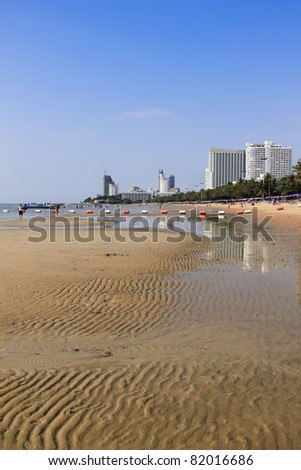pattayas heavily developed beachfront with large hotels reflecting in the water of tidepools along the sandy beach