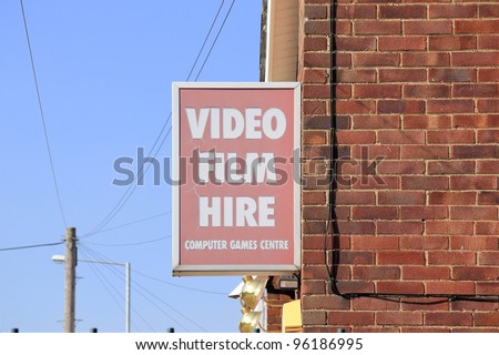 old faded sign hanging on brick wall advertising video film hire and computer games centre