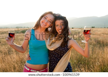 Happy girl friends drinking wine during the golden evening hour