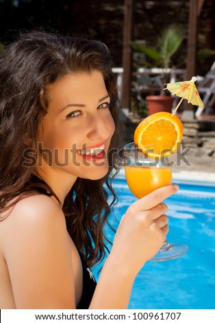 Pretty model drinking a cocktail at the poolside