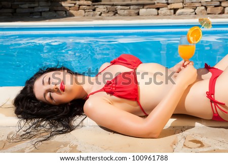 Young model having a cocktail drink at the poolside