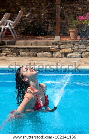 Vacation image of a young woman giving herself a shower with a water hose