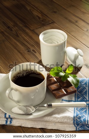 Powder stevia and stevia chocolate next to a cup of coffee without sugar