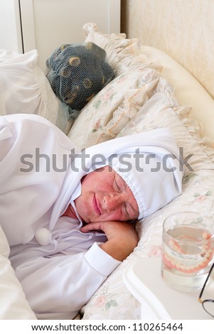 Eldery couple in vintage nightwear asleep in bed
