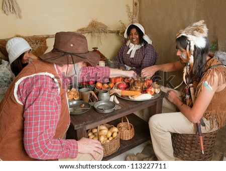 Reenactment scene of the first Thanksgiving Dinner in Plymouth in 1621 with a Pilgrim family and a Wampanoag Indian