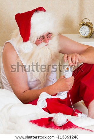 Funny Santa Claus mending his own socks