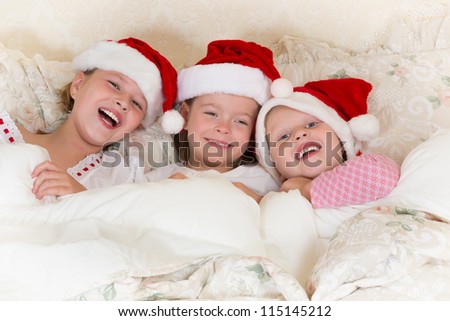 Laughing little girls in bed with santa hats on