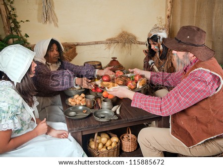 Reenactment scene of the first Thanksgiving Dinner in Plymouth in 1621 with a Pilgrim family and a Wampanoag Indian