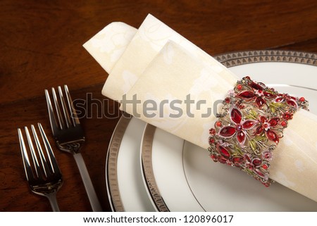 Cream colored festive napkin with ornate fancy napkin ring on a holiday table