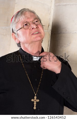 Mature cardinal annoyed by the pinching priest collar in his shirt or cassock