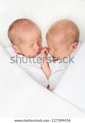 Adorable newborn twin brothers sleeping in a white towel