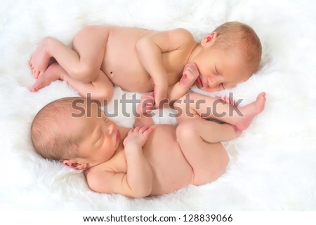 Newborn baby twins sleeping in Ying Yang position, holding hands