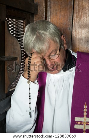 Vicar or priest sitting in a confession booth and listening to sins