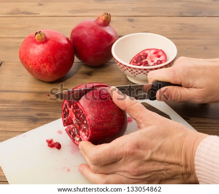 Hands cutting a pomegranate in four quarters