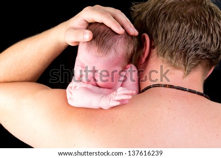 Young Dad holding his newborn baby over his shoulder