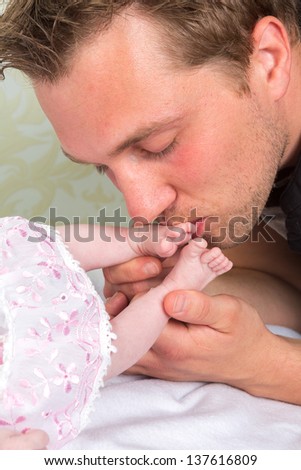 Feet of a newborn baby being kissed by father