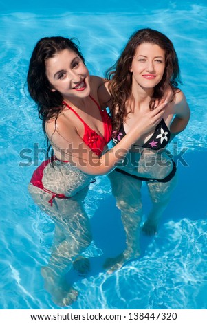 Girl-friends posing in bikini in a swimming-pool