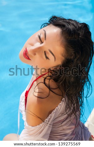 Sensual woman sitting near the swimming pool on a hot day