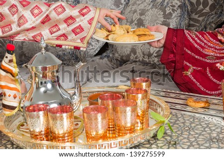 Traditional Moroccan immigrant women presenting typical Ramadan cookies and tea