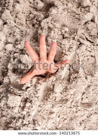 Hand on a beach sinking or drowning in quicksand