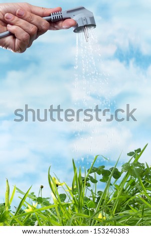 Electrical plug watering a green grass meadow as a symbol of green and renewable energy