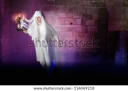 Pale woman in nightgown sleepwalking or a ghost in a medieval castle