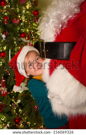 Happy little girl giving santa claus a big hug