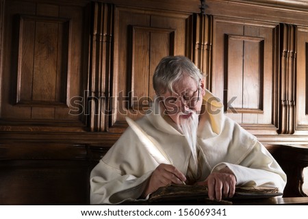Old monk in habit writing with a feather quill