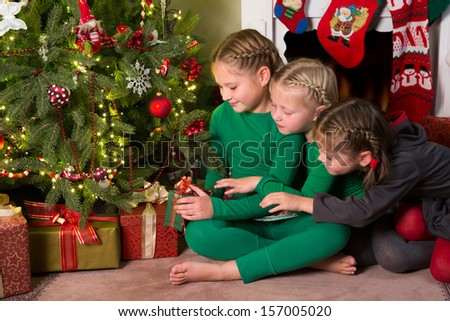 Three young girls looking at the presents under their christmas tree